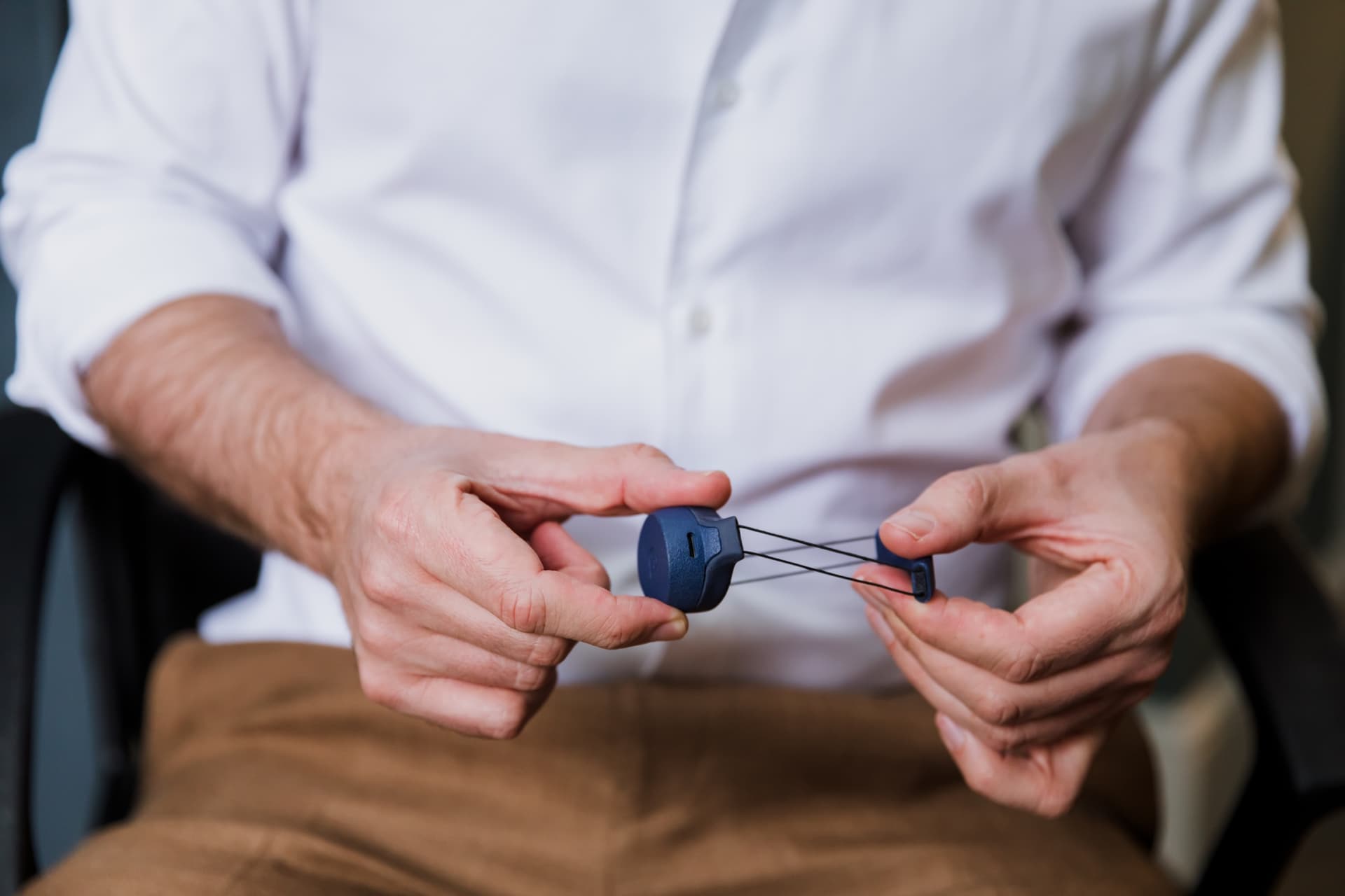 An Adam sensor held in both hands, the small monitor used to record erections overnight