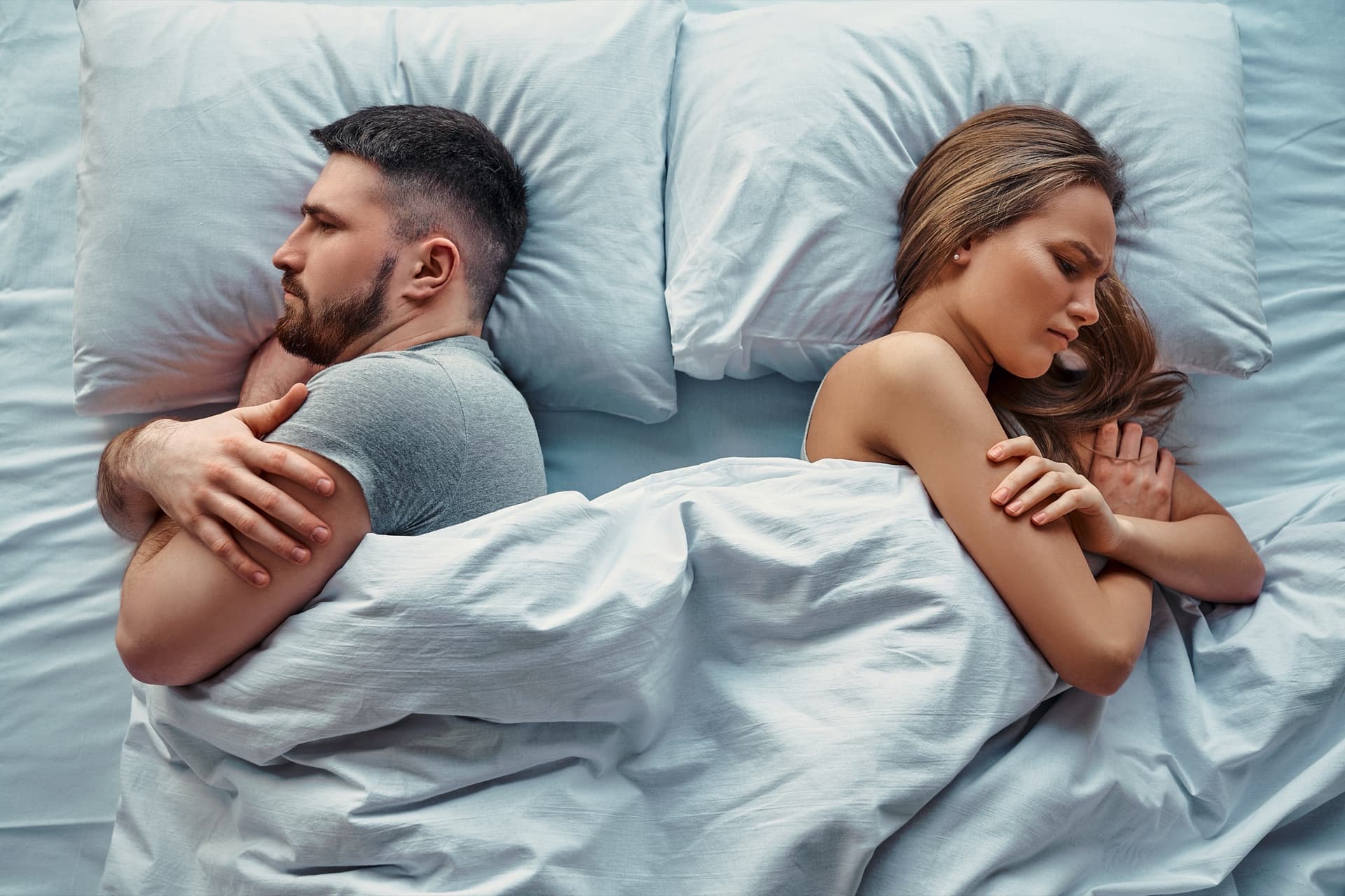 A couple in bed, turned away from one another