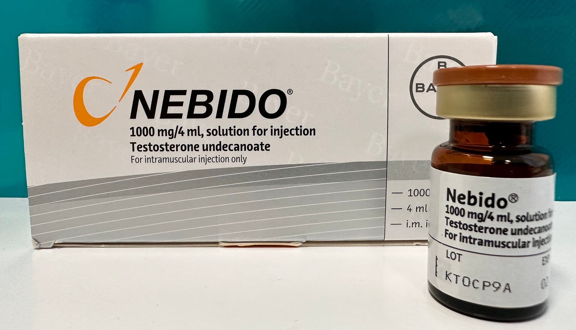 A vial of Nebido 1000mg/4ml testosterone undecanoate beside its box.