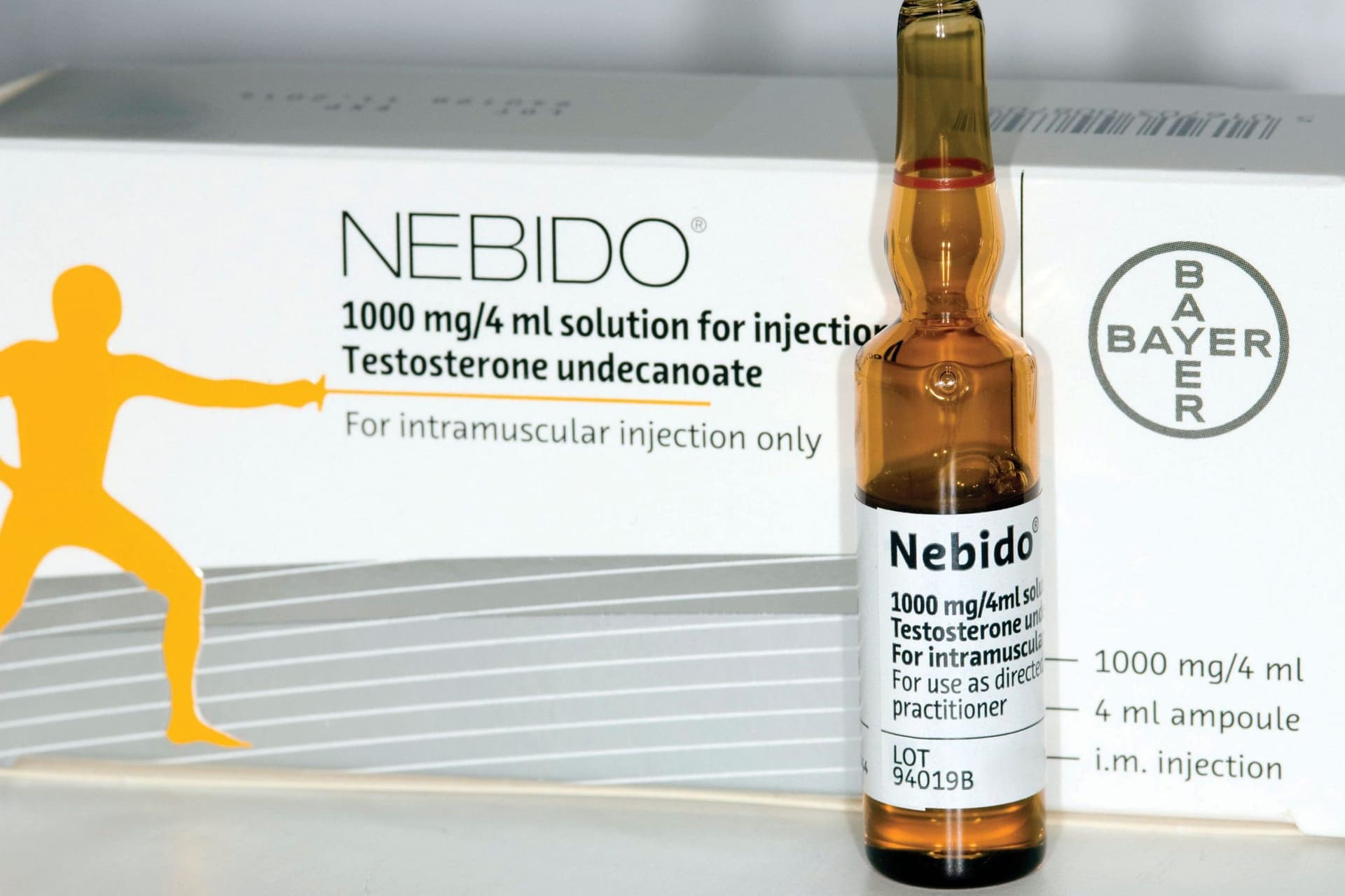 A single amber ampoule of Nebido 1000mg/4ml testosterone undecanoate standing in front of its box.